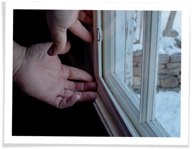 A person touching their window frames in order to check for a window
			leak.