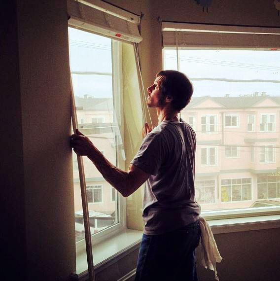 Man installing Indow insert behind blinds in his bay window