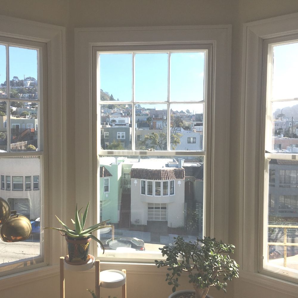 A view from a bay window with Indow inserts. The view looks towards
			the neighborhood houses. 