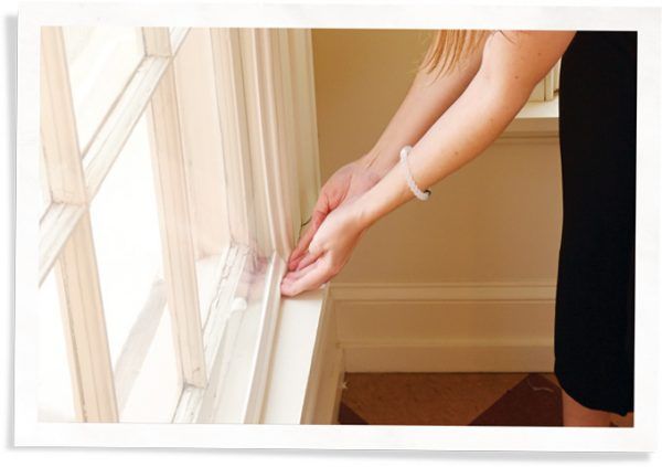 A person installs a soundproofing window insert from Indow into a window frame.