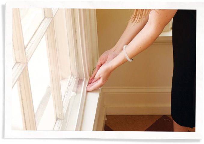 A woman is pushing the bottom right corner of a window insert replacement into place.